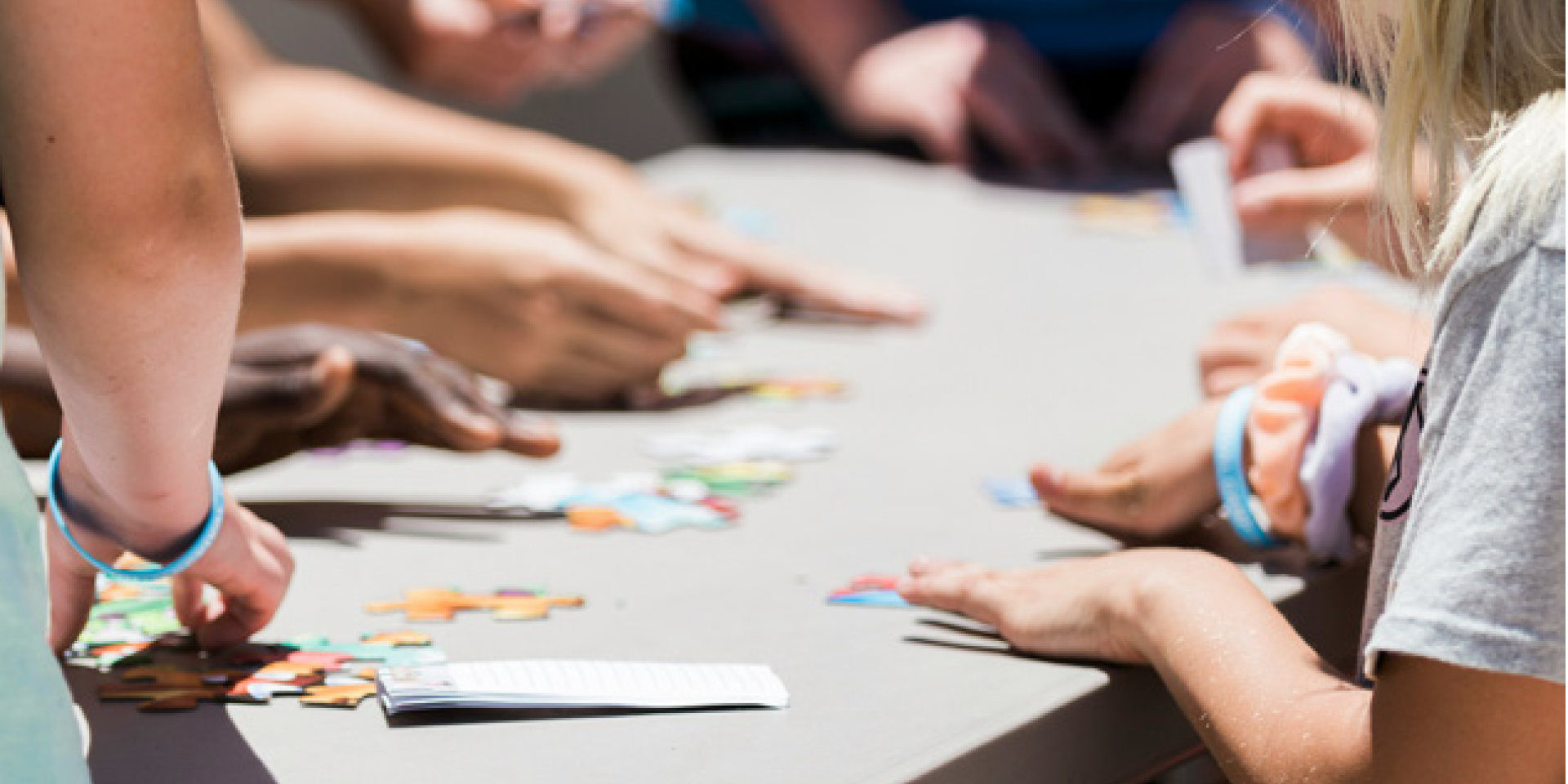 Gruppe von Personen sitzt um einen Tisch und hält Karten mit verschiedenen Symbolen und Farben in den Händen. Die Szene zeigt eine interaktive Übung oder ein Spiel, bei dem die Teilnehmer:innen Karten auswählen oder sortieren.